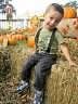 Child sitting on hay bale with pumpkins in background