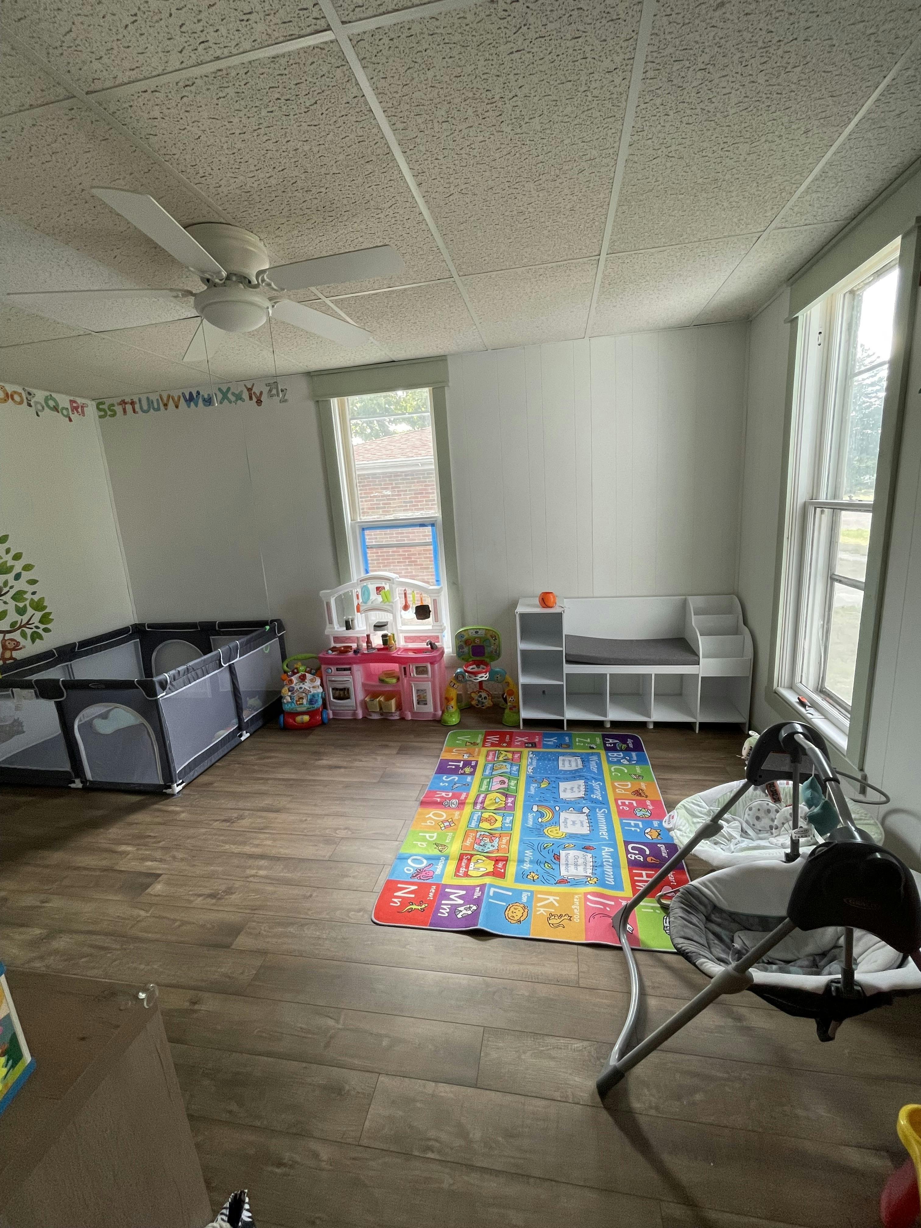 Playroom with a playpen, colorful rug, and baby swing