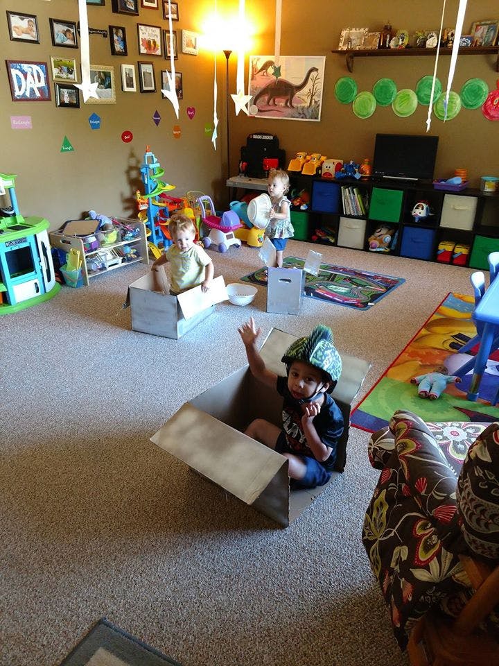 Three children playing with cardboard boxes in a playroom