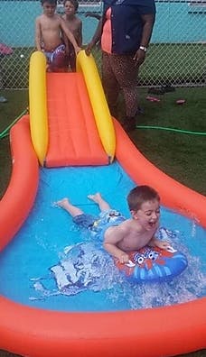 Child sliding down an inflatable water slide into a pool