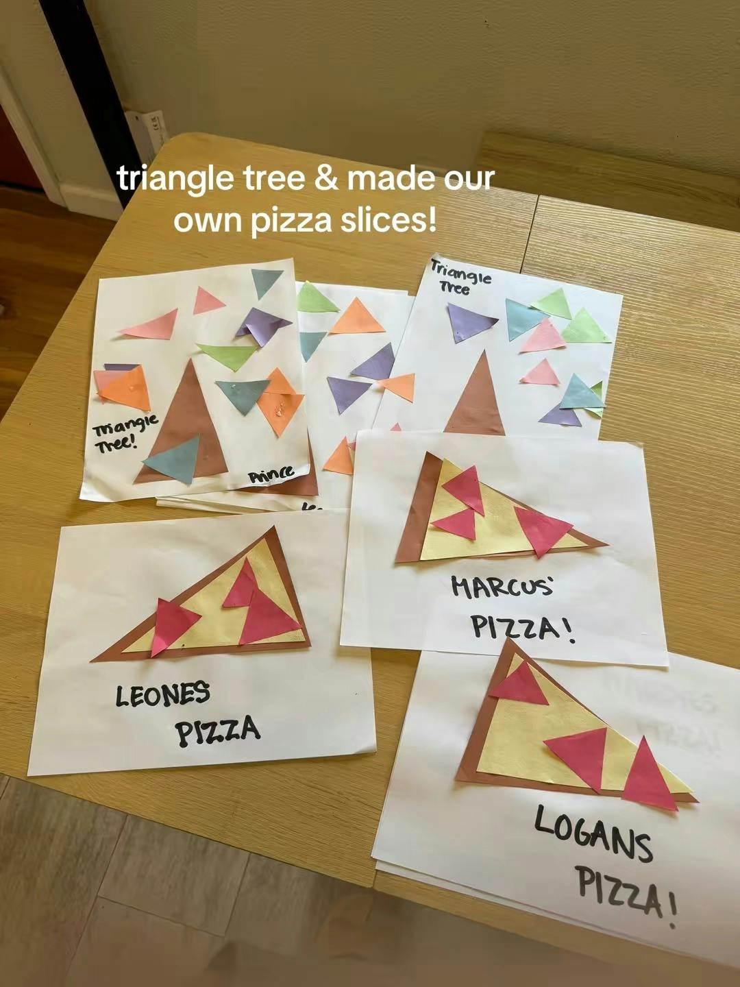 multiple construction paper triangle tree and pizza craft projects on a table