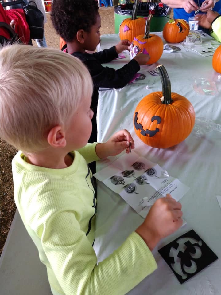 Two children decorating pumpkins with stickers