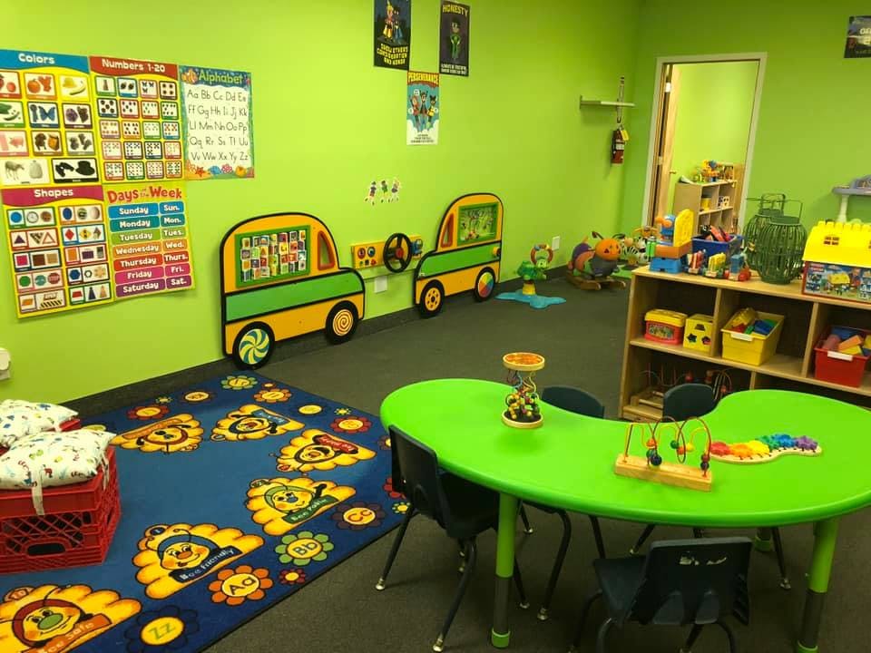 Classroom with green walls, a blue rug, and a green table with chairs