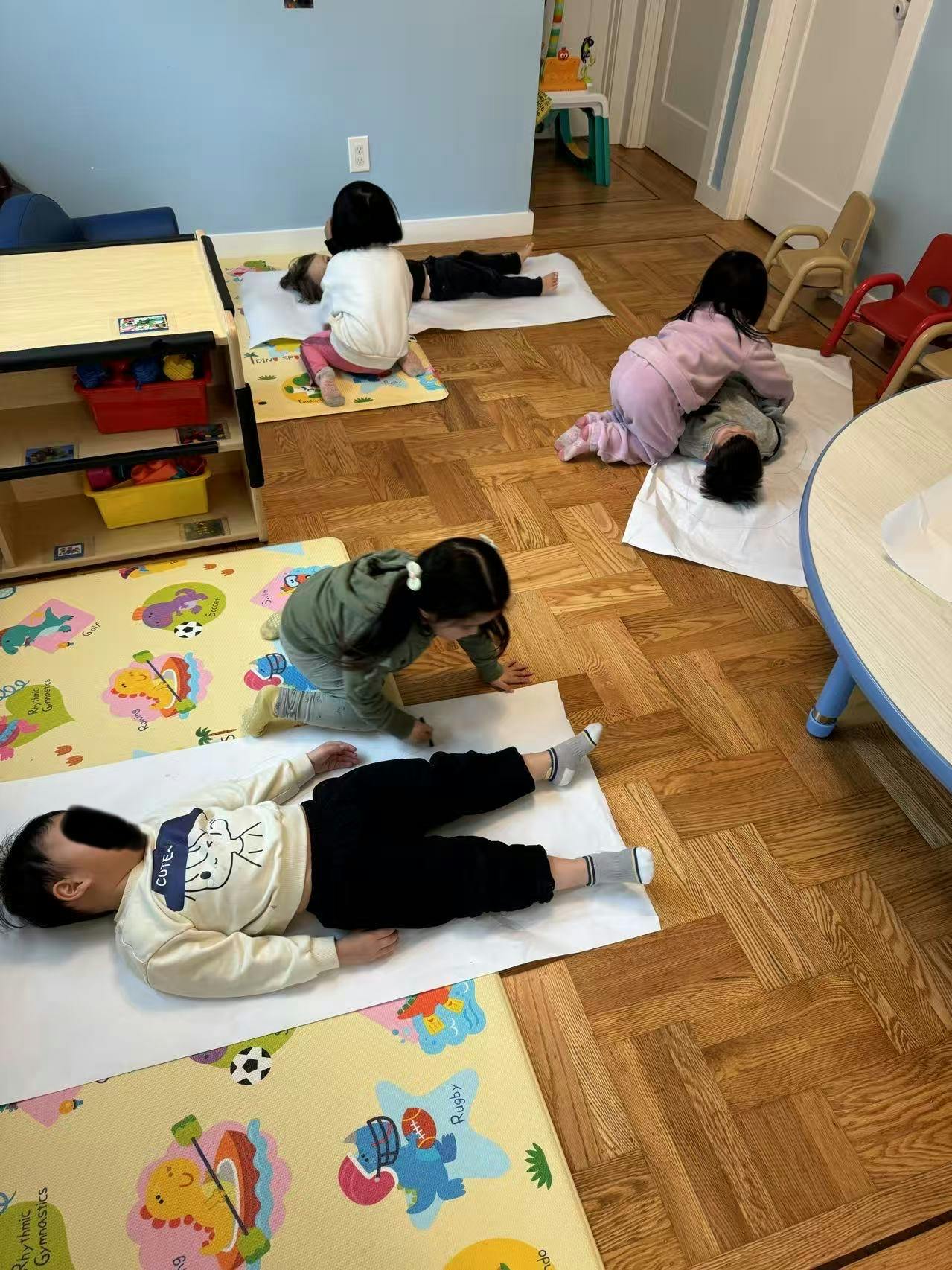 Children lying on mats on a wooden floor