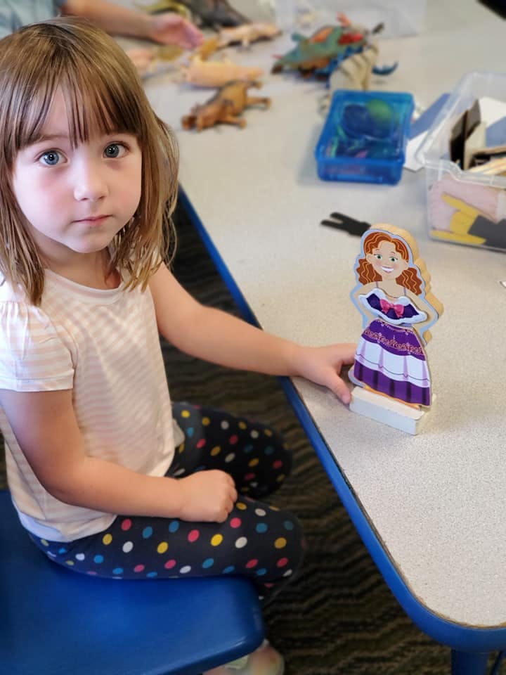 Child sitting at a table with a doll cutout figure