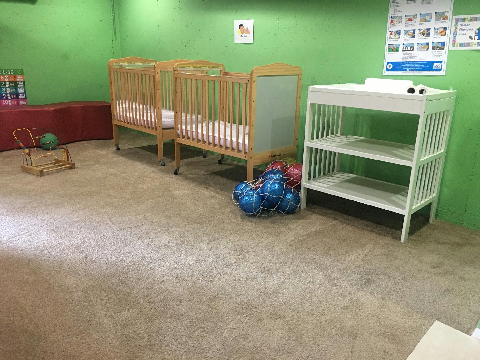 Two cribs and a changing table in a room