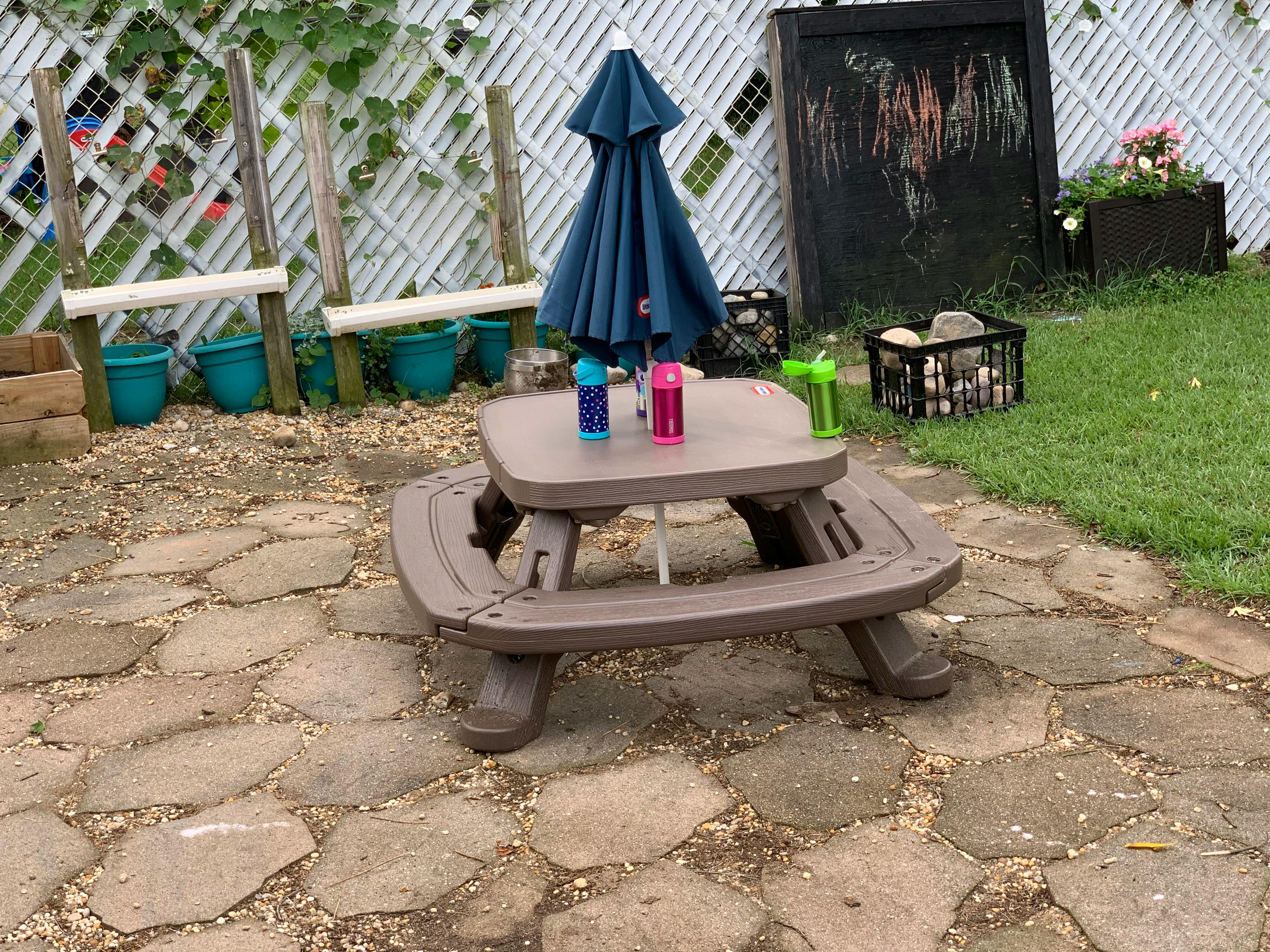 Small picnic table with an umbrella and two water bottles on a patio