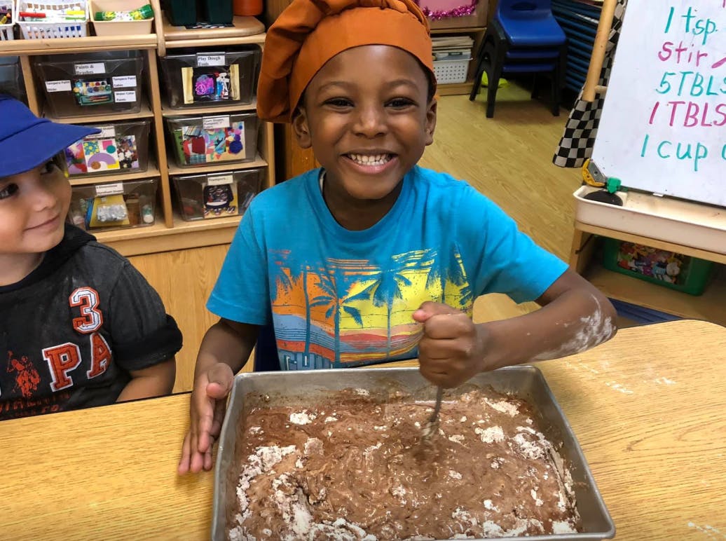 Child in chef hat mixing ingredients in a pan