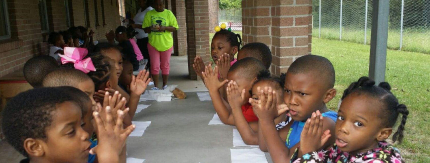 Group of children sitting with hands together
