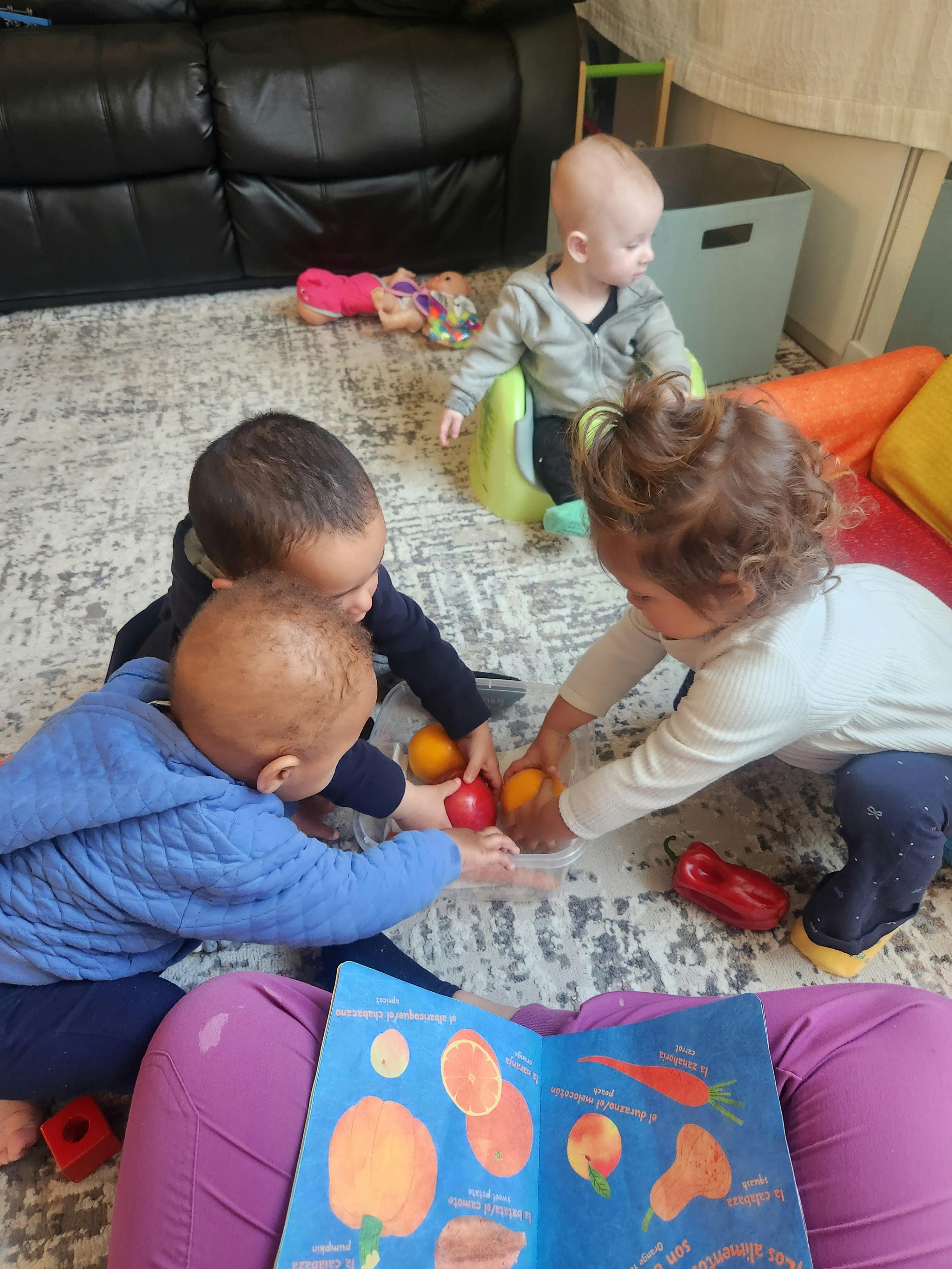 Four children playing with toy fruit and vegetables on a rug