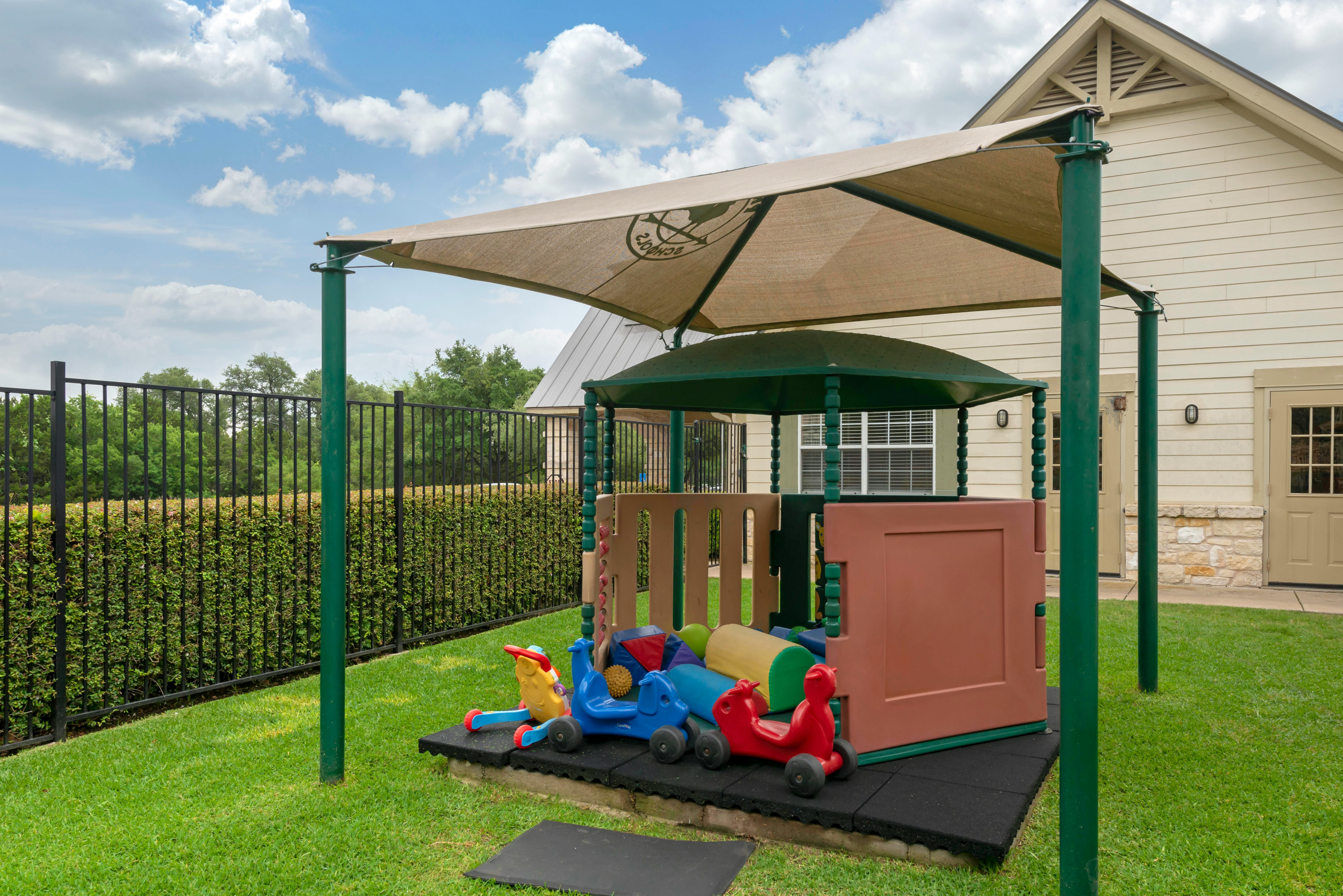 Outdoor play area with a sunshade covering a small play structure