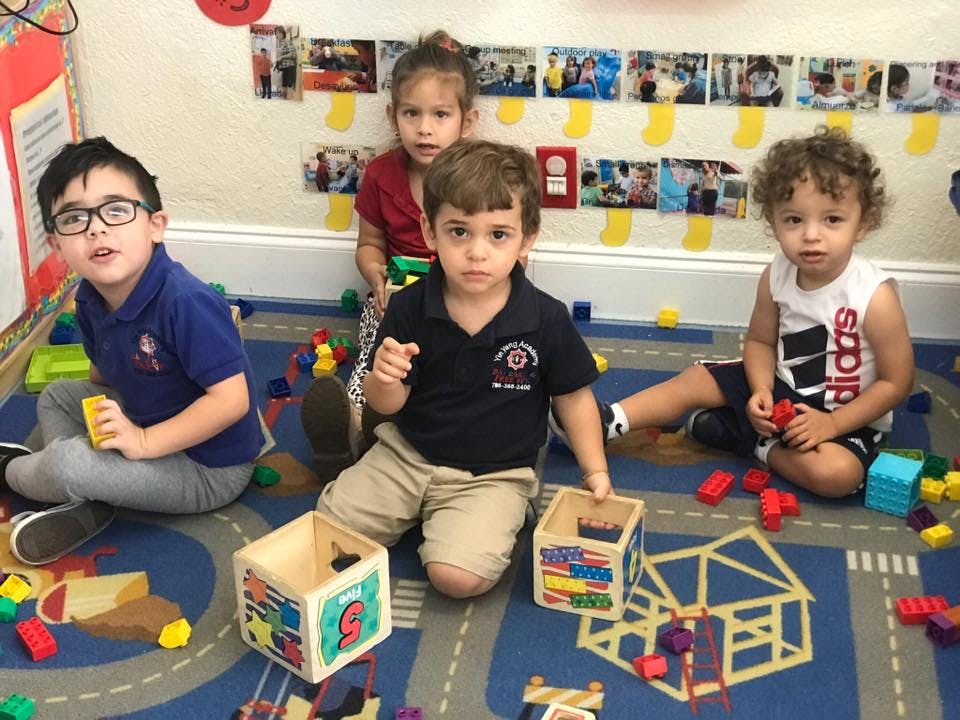 Four children playing with blocks on a rug