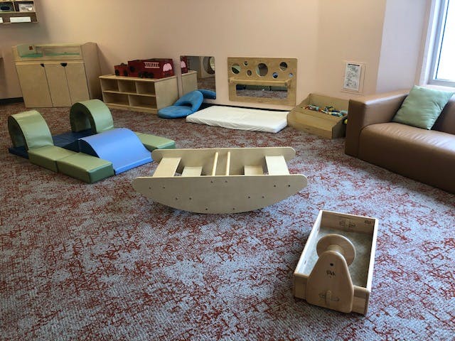 Playroom with soft play equipment, wooden rocker, and small couch