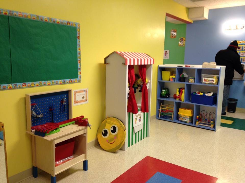 Classroom with a puppet theater, toy workbench, and shelves of shelves with a person