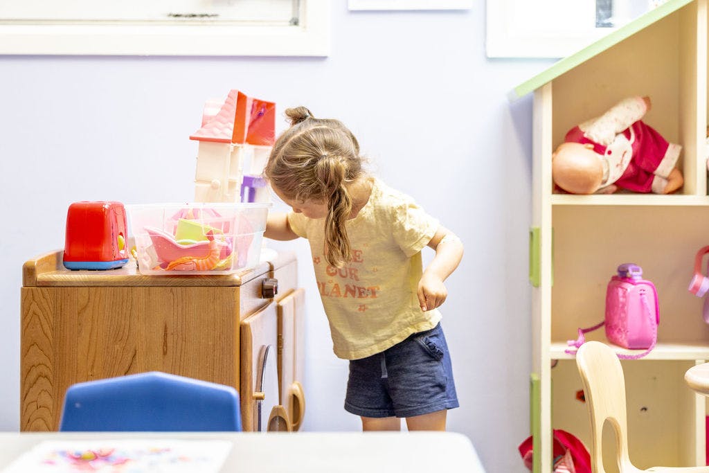 Child looking into a toy box in a classroom
