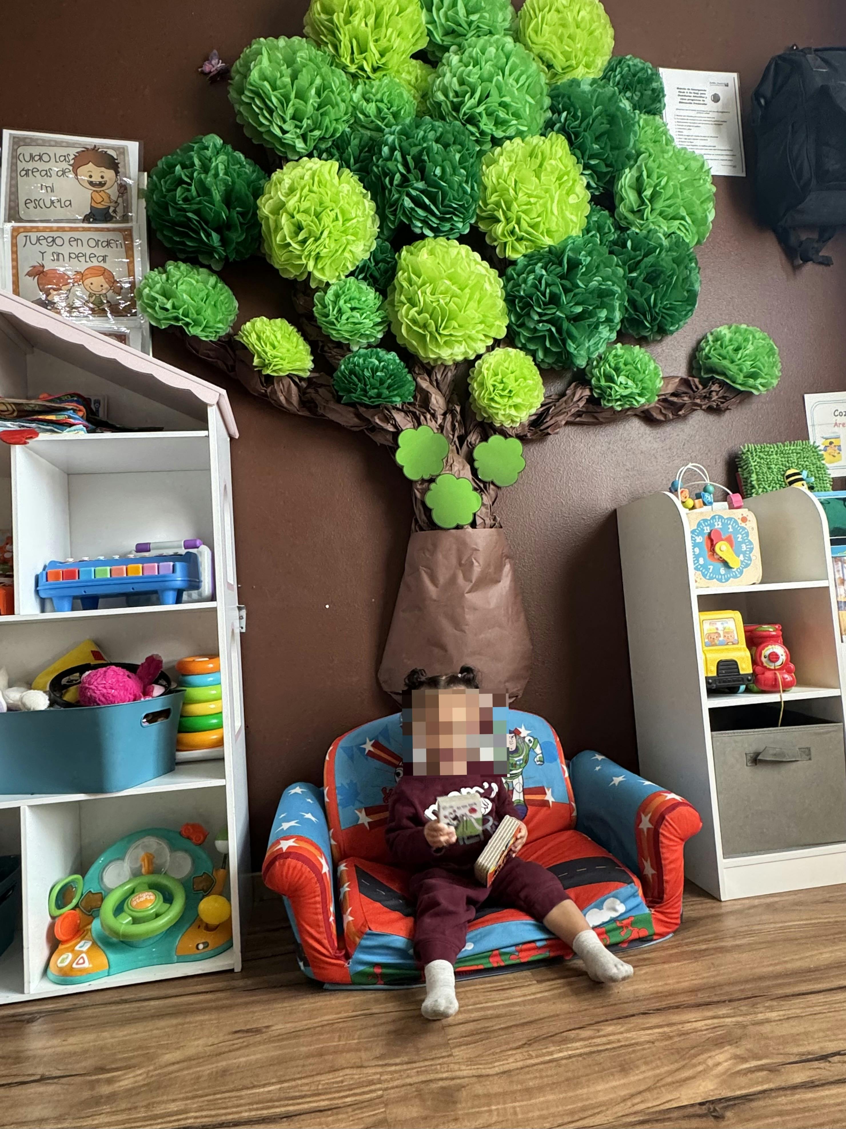Child sitting on a small couch reading a book in a classroom