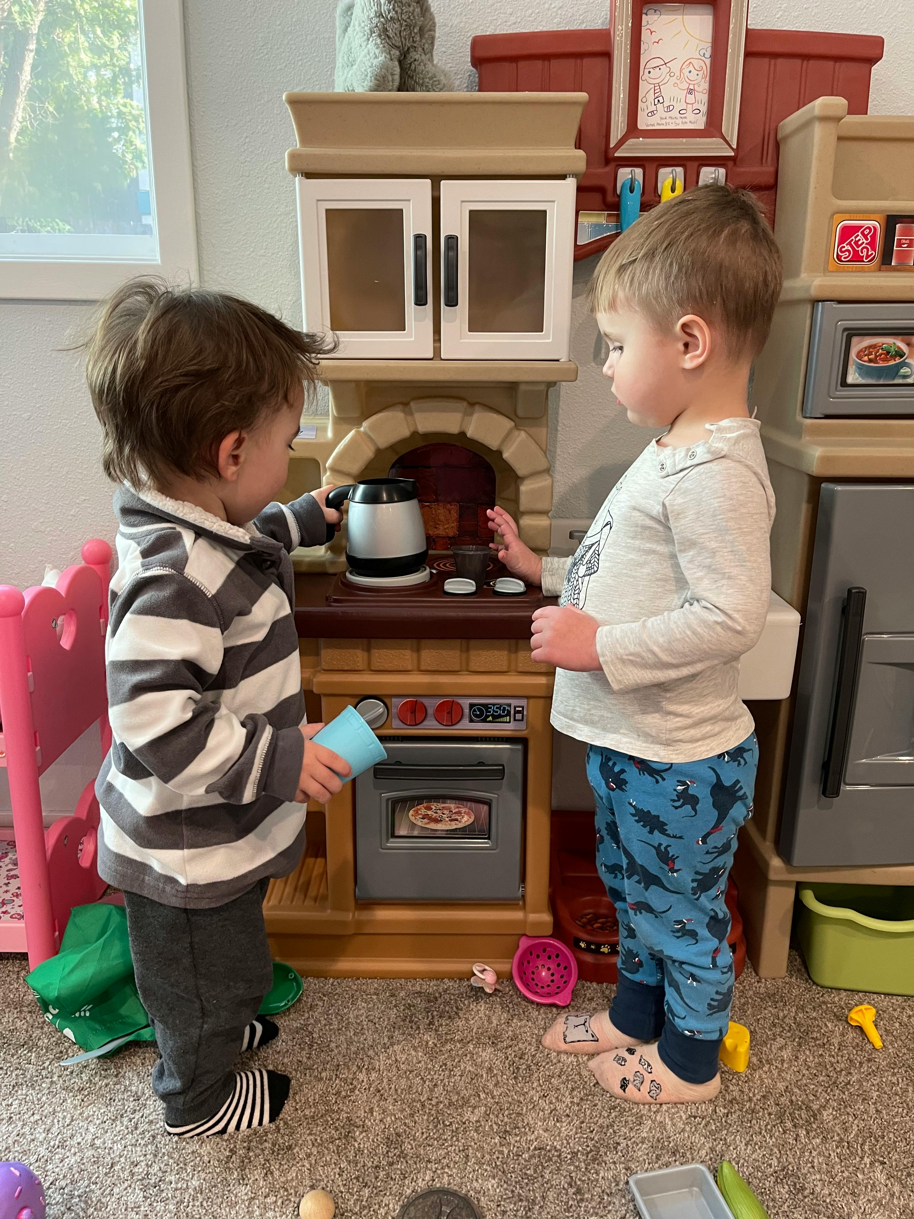 Two children playing with a toy kitchen set