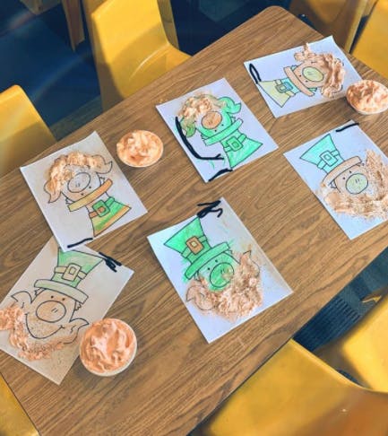 Leprechaun drawings with textured beards on a wooden table