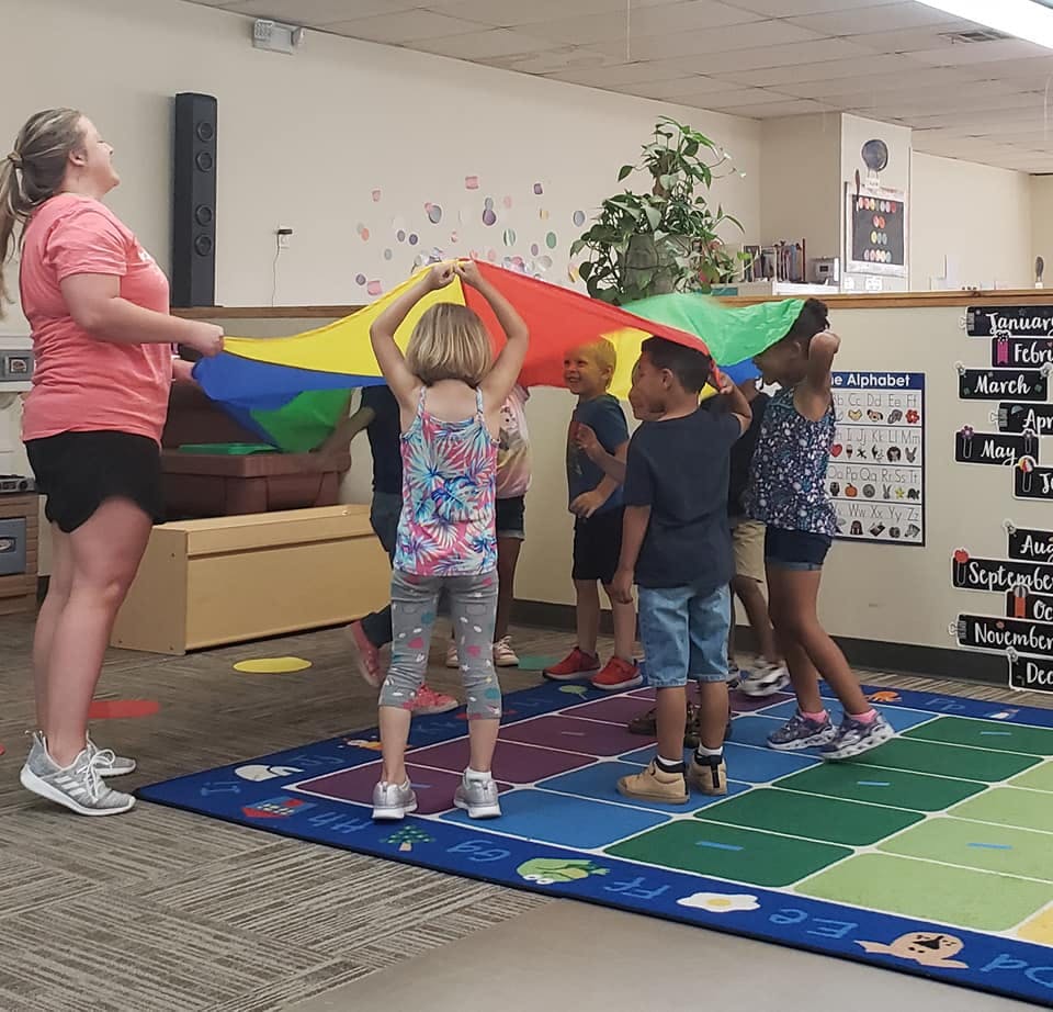 Adult and children playing with a colorful parachute