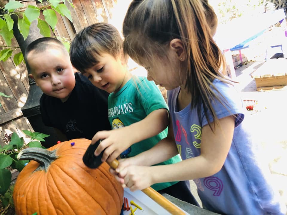 Three children carving a pumpkin