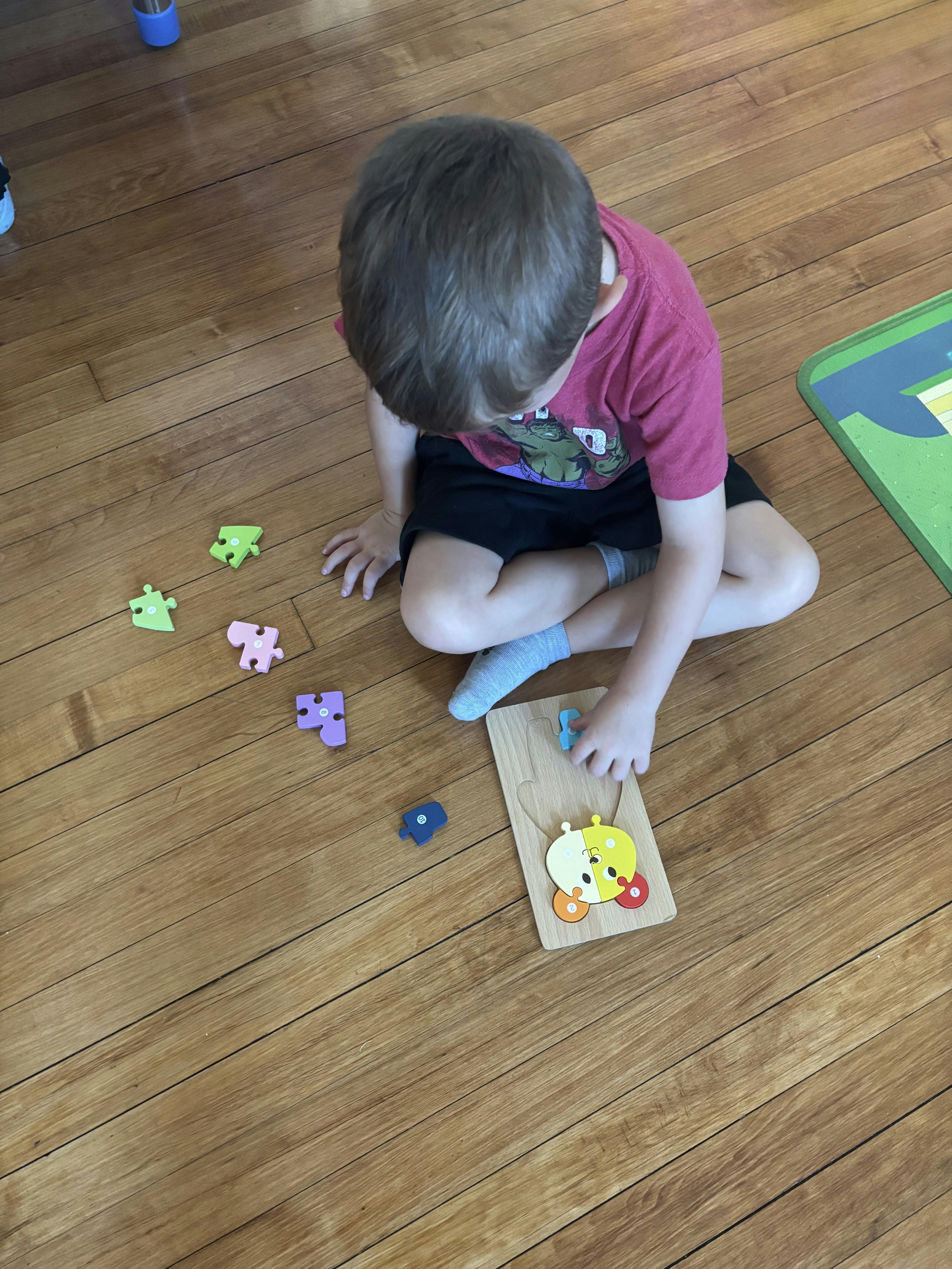Child sitting on floor playing with a wooden puzzle