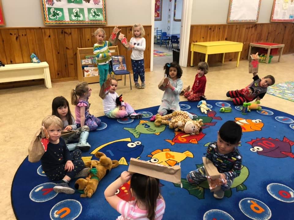 Children playing with toys on a blue rug in a classroom