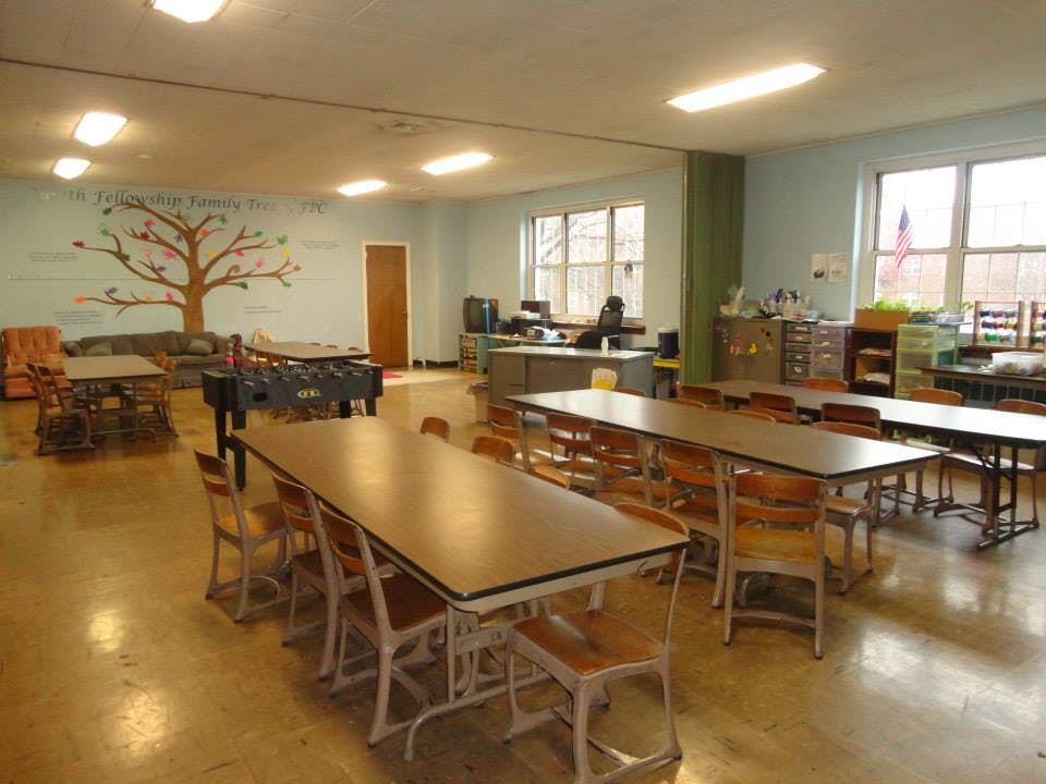 Classroom with long tables and chairs, a foosball table, and a tree mural