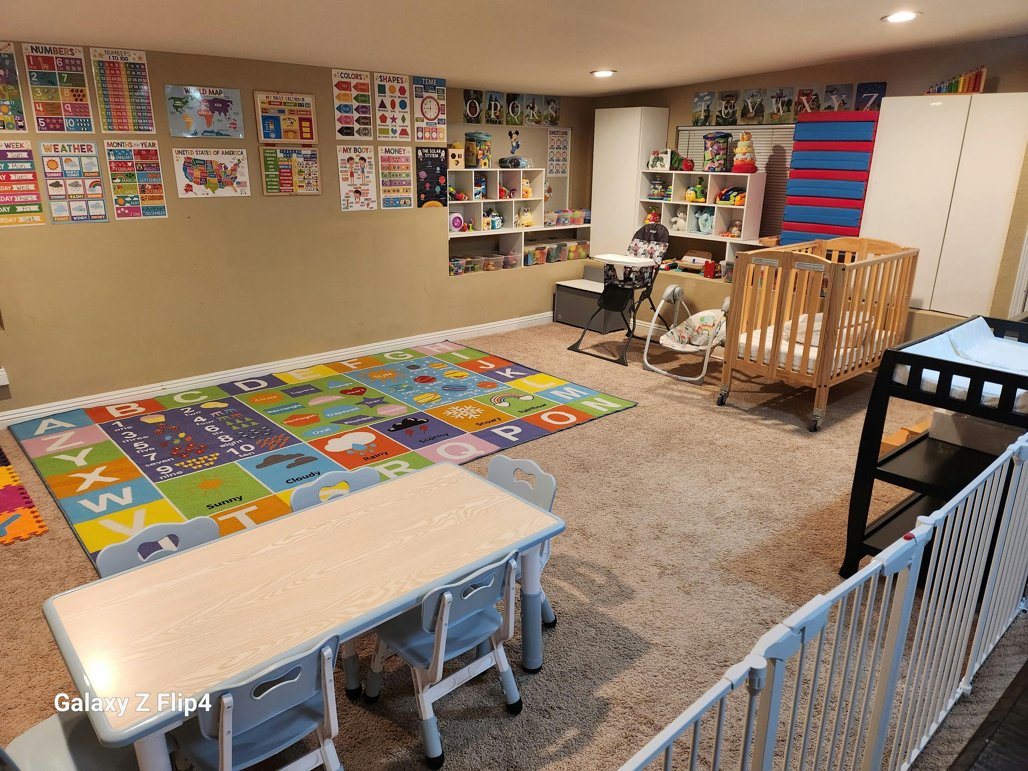 Childcare playroom with educational wall posters, play mat, and crib