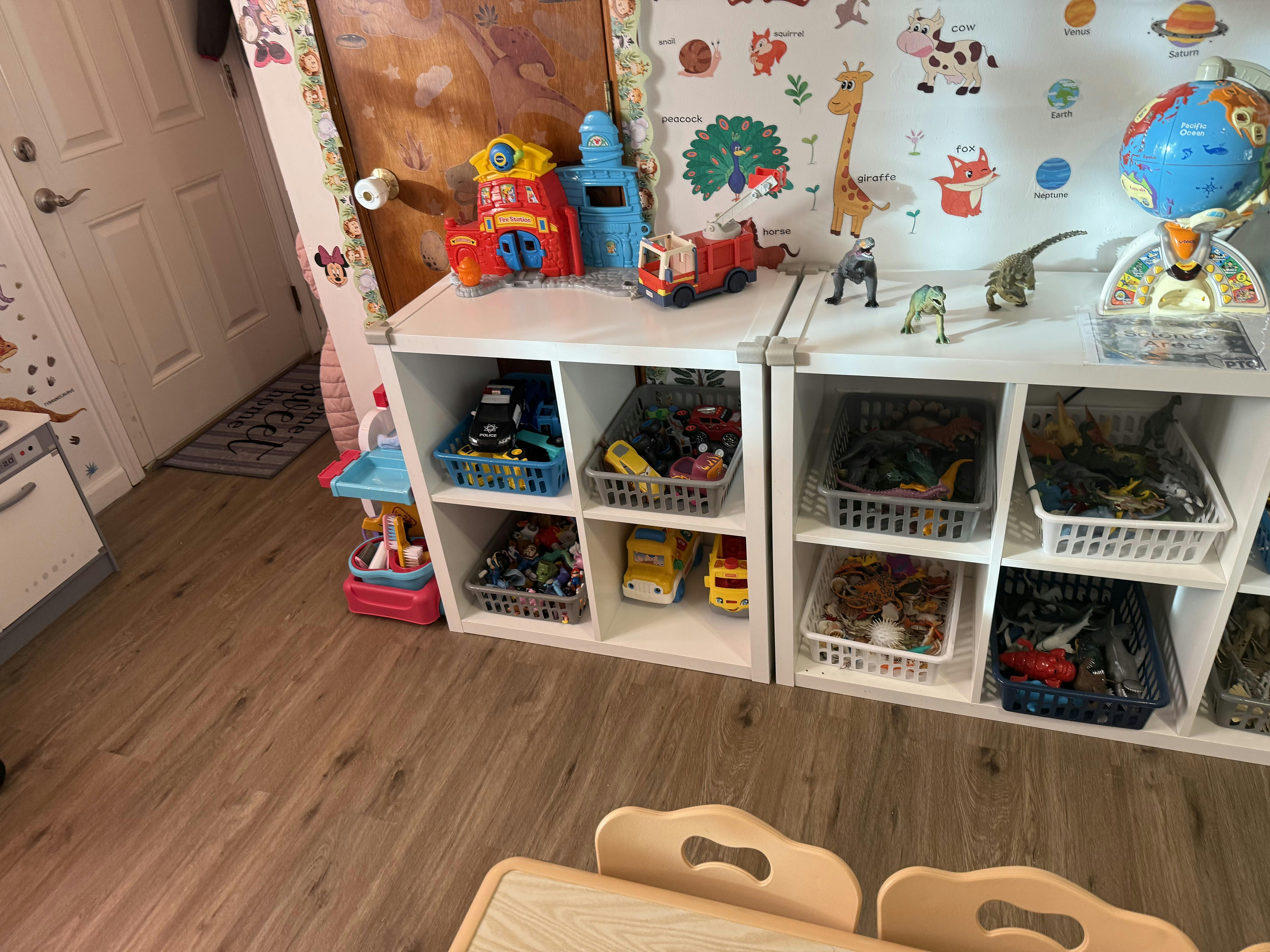 Children's room with toy storage shelves, fire station, fire truck, and dinosaurs