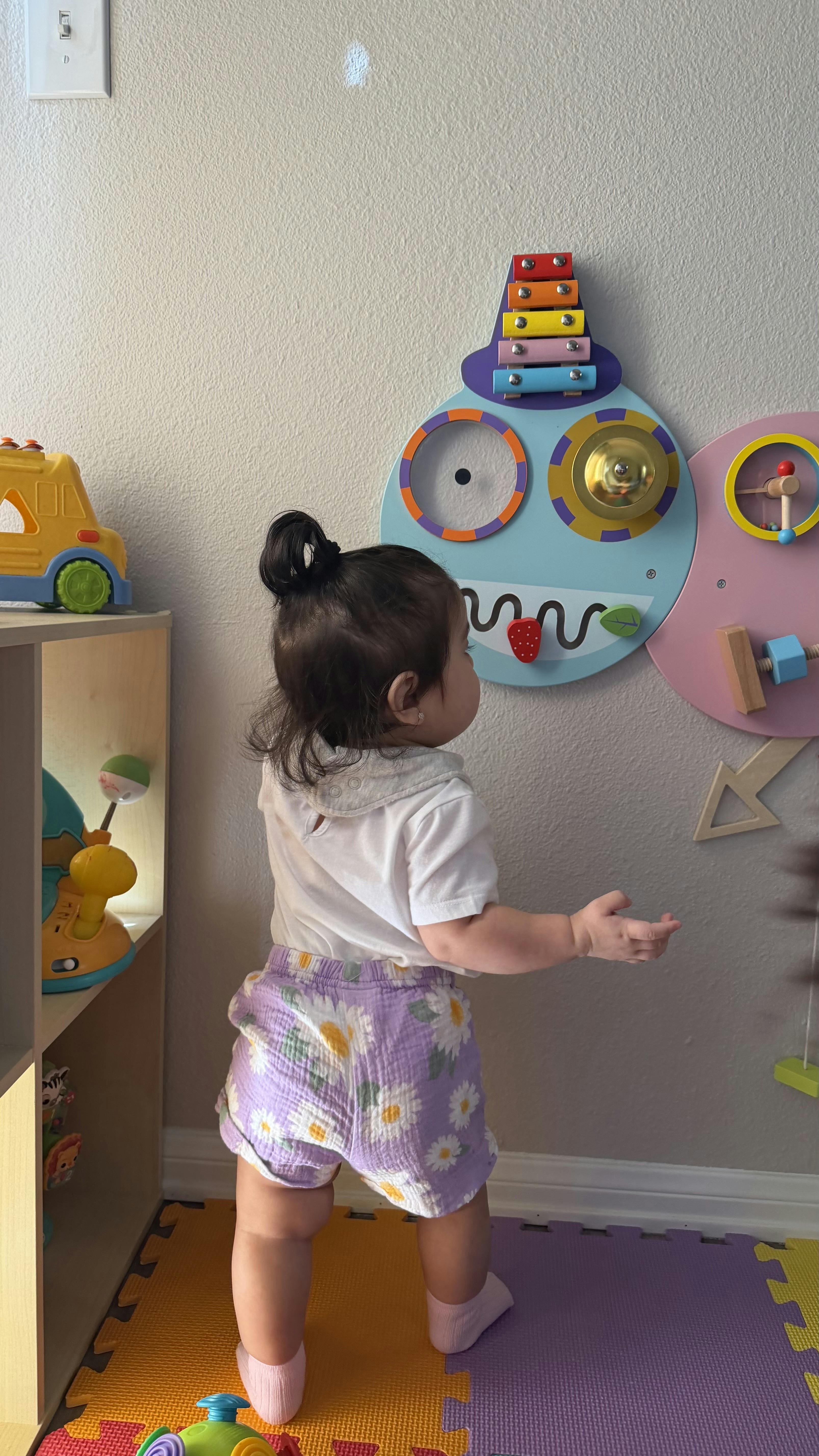 A small child playing with a mounted wall activity center
