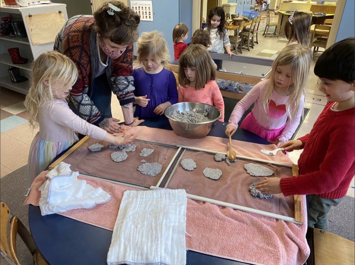 Adult and children making paper in a classroom