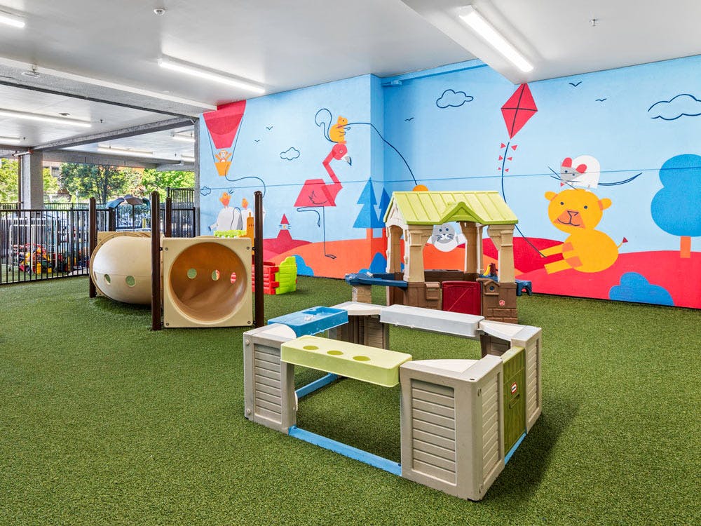 Indoor playground with tunnel, playhouse, and colorful murals