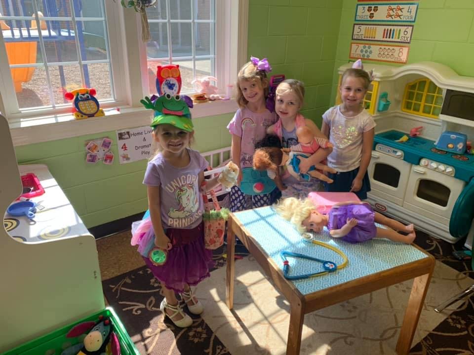 Children playing with dolls and toys in a room