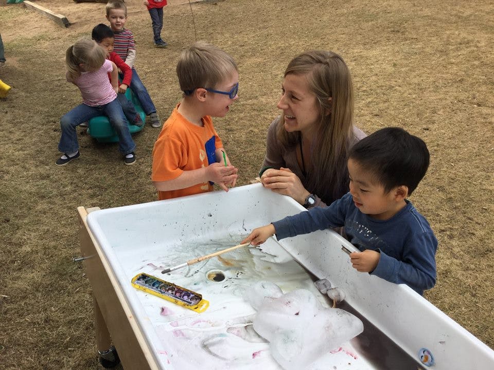 Adult and two children playing with water table