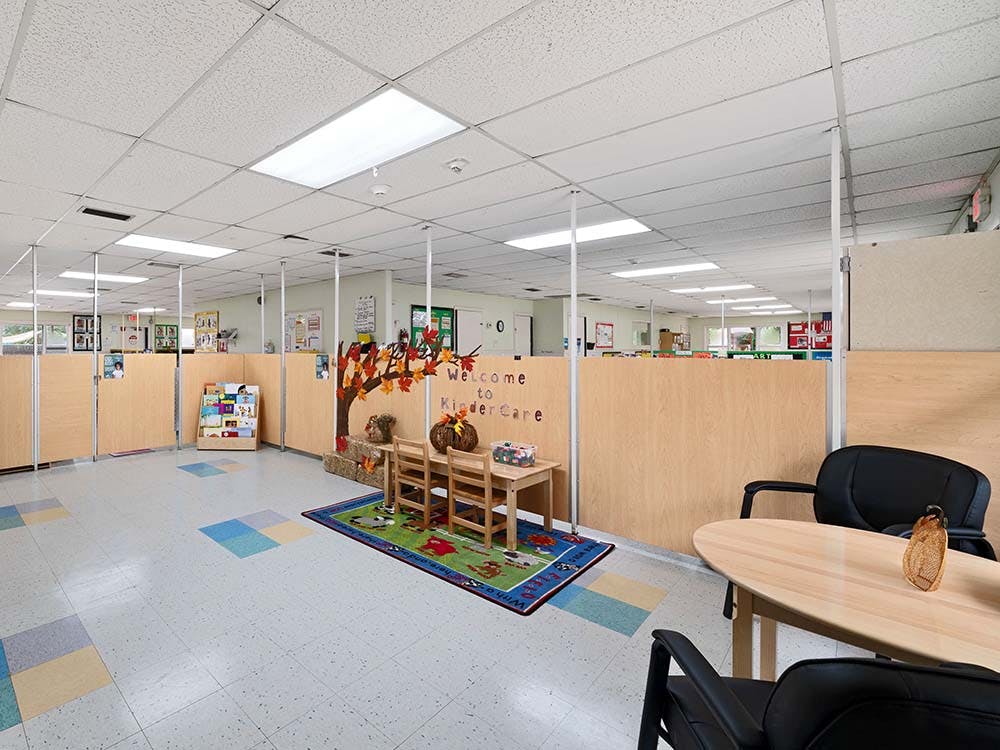 Classroom with dividers, small tables and chairs, and a welcome sign
