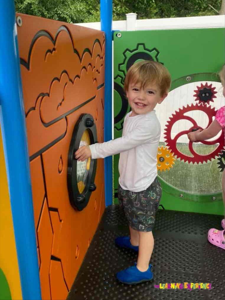 Child playing with a porthole on a playground structure