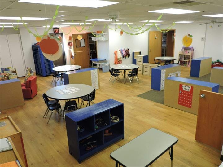 Empty classroom with tables, chairs, and storage units
