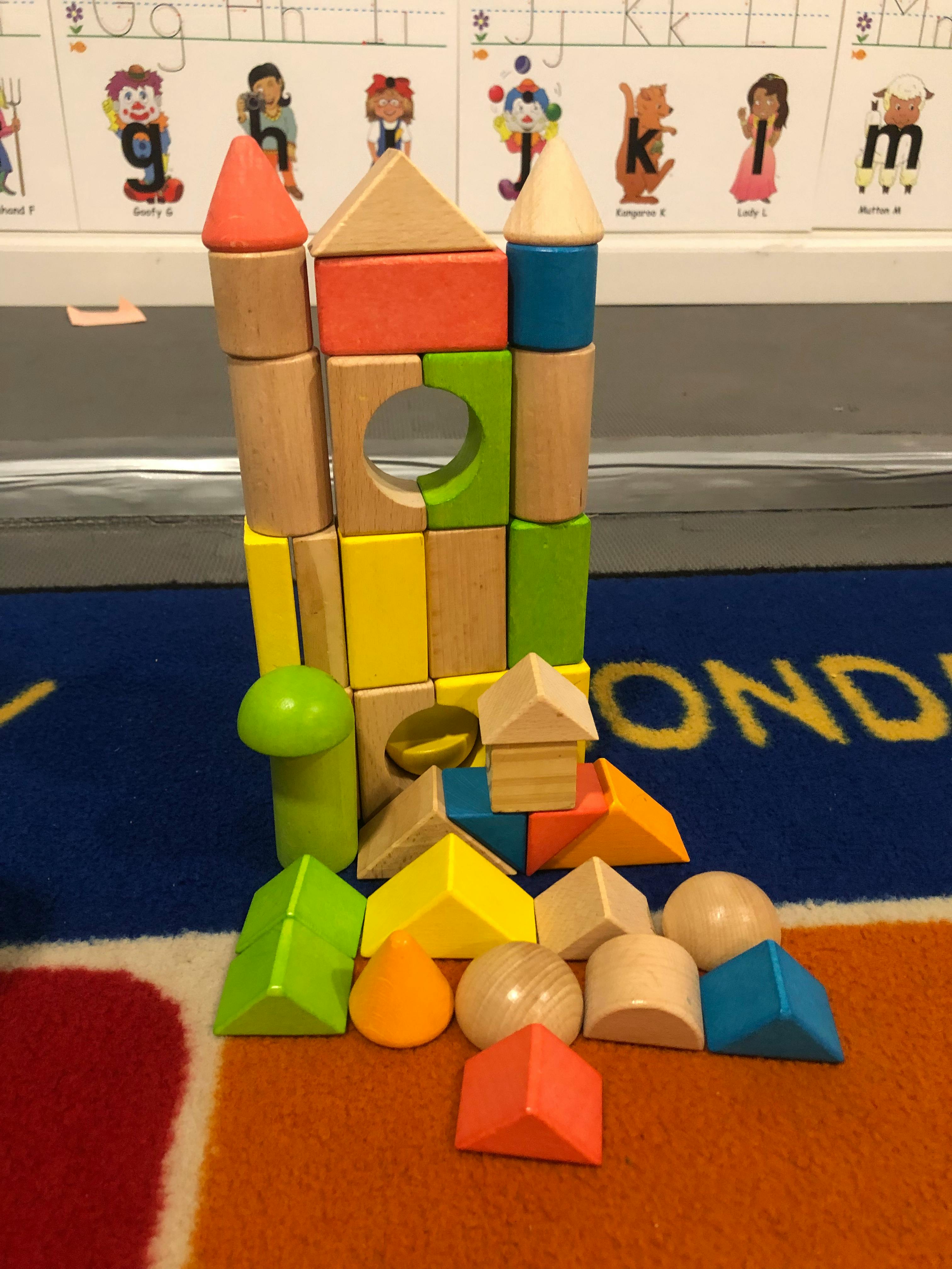 Colorful wooden building blocks stacked into a tower with loose blocks around it