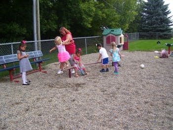 Adult and children playing on a seesaw on a playground