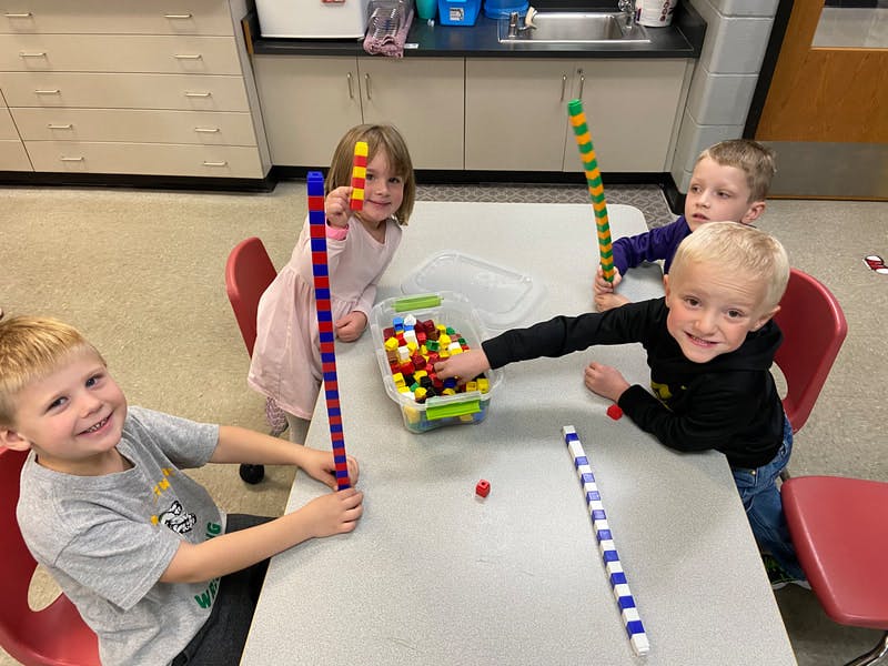 Four children playing with colorful building blocks at a table