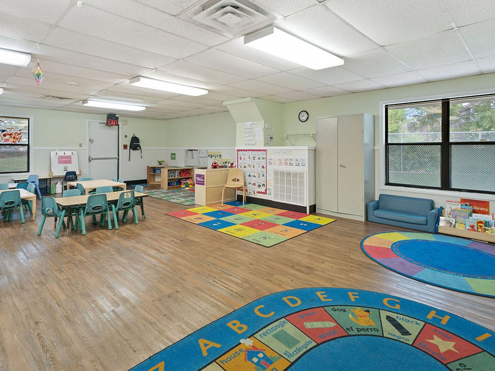 Empty classroom with tables, chairs, and colorful rugs on the floor