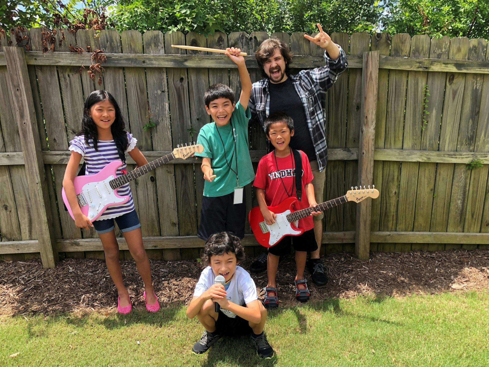 Adult and four children with musical instruments outdoors