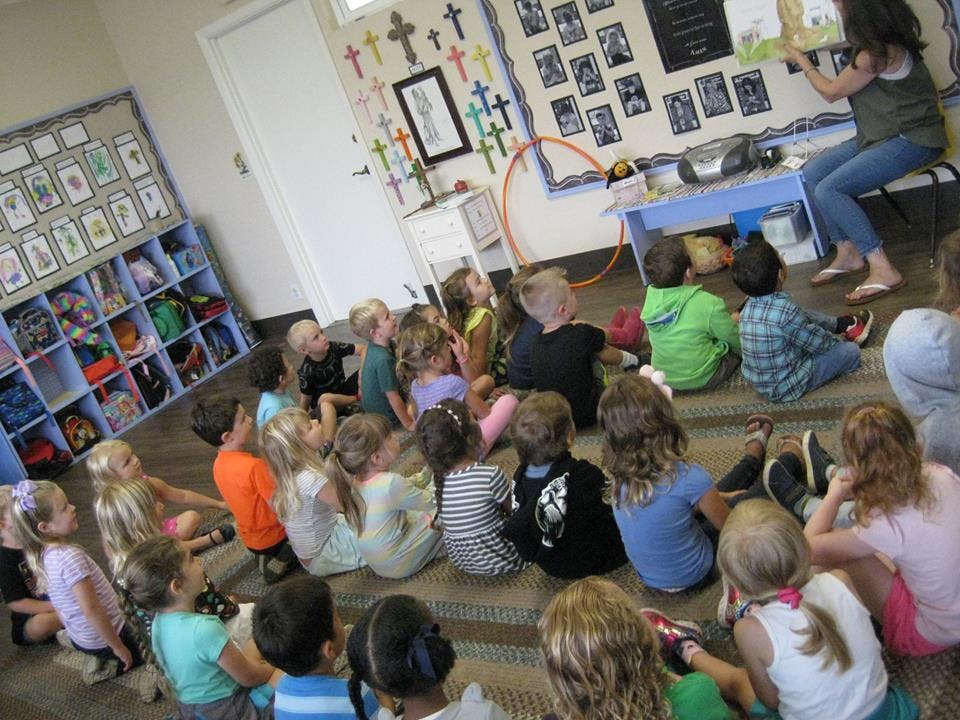 Person reading to a group of children in a classroom