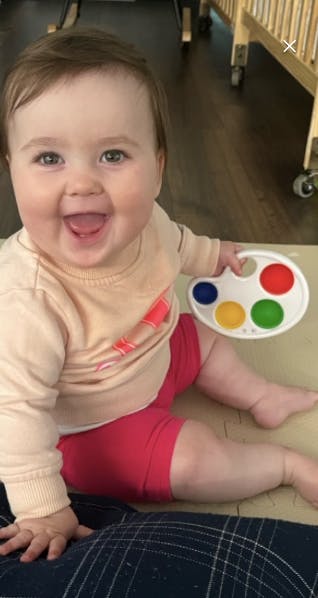 Child sitting and holding a toy paint palette