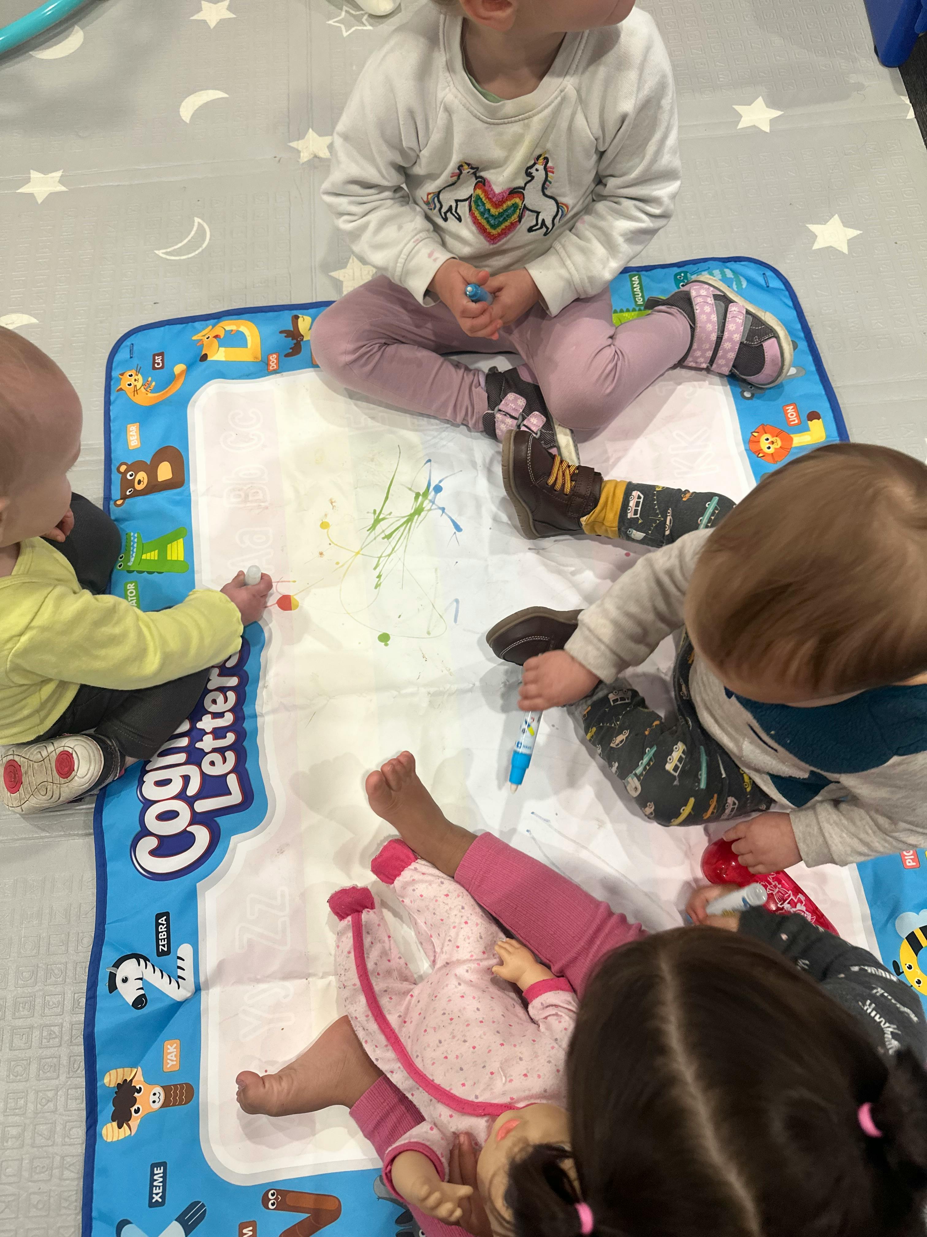 Children playing on a mat with paint