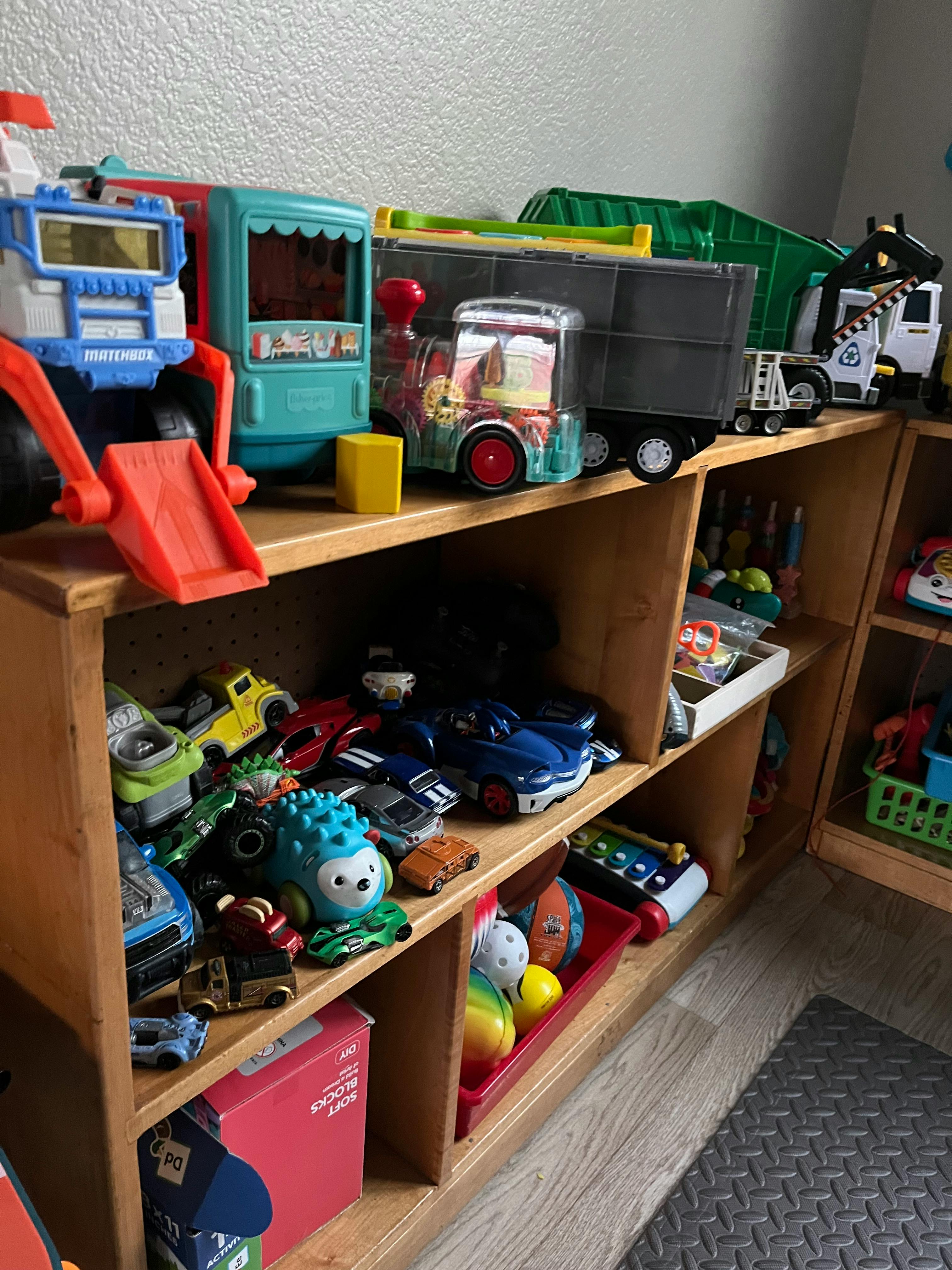 Wooden shelves filled with various toy vehicles and other toys