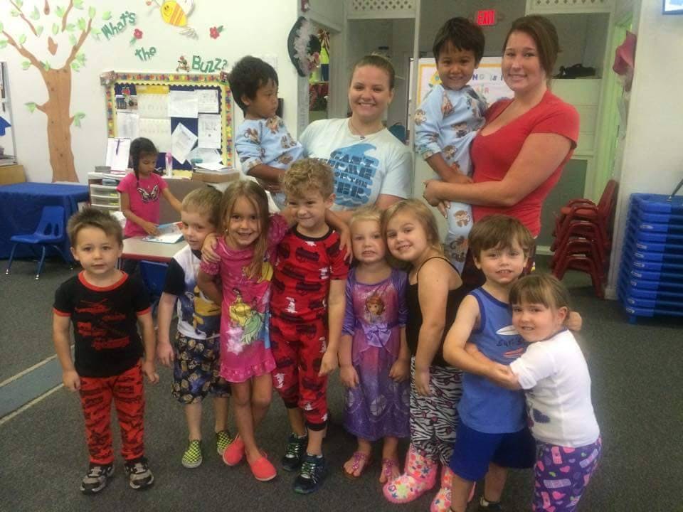 Two adults with a group of children in a classroom
