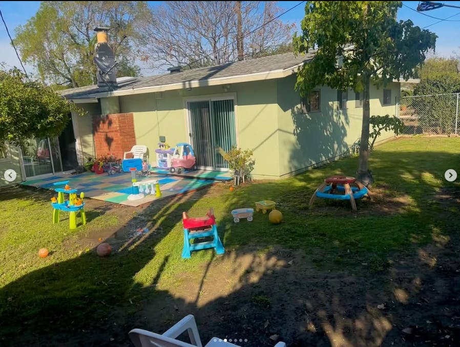 Backyard with a house and children's toys on a patio and grass