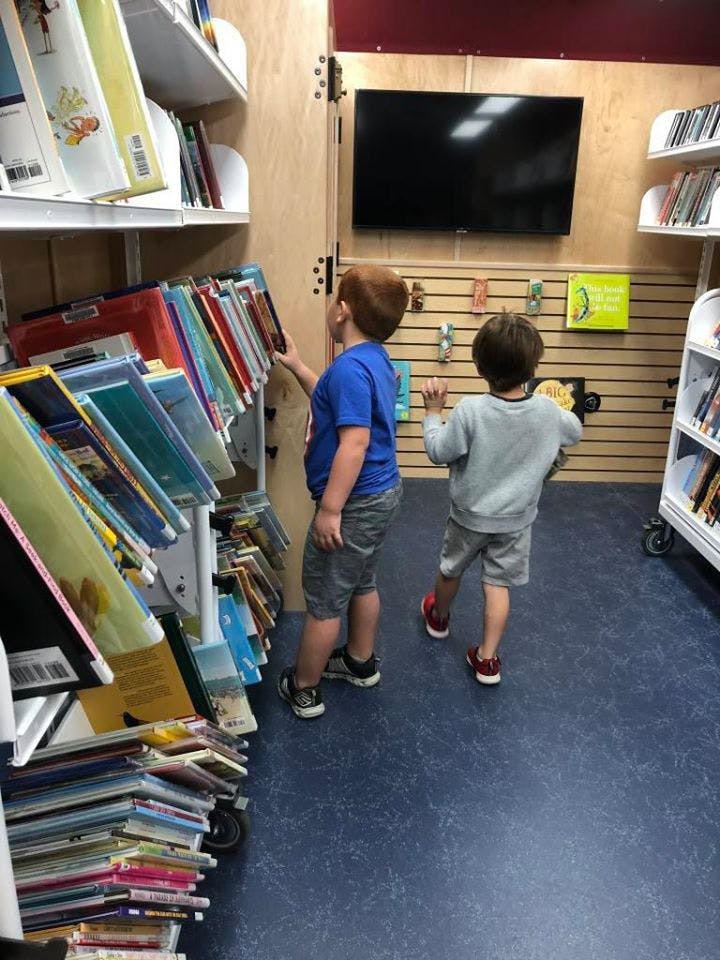 Two children looking at books on shelves in a library
