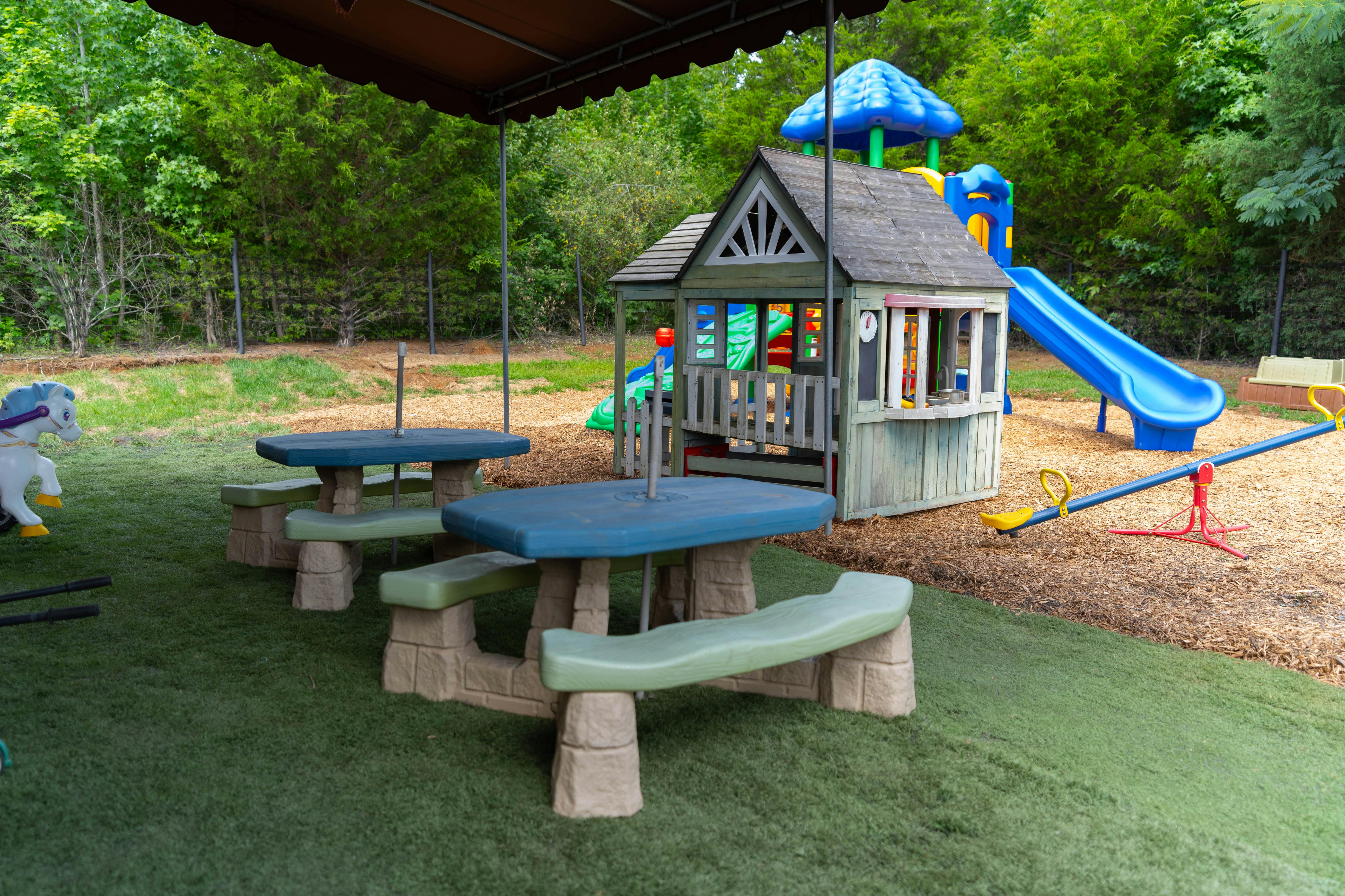 Playground with picnic tables, playhouse, slide, and seesaw
